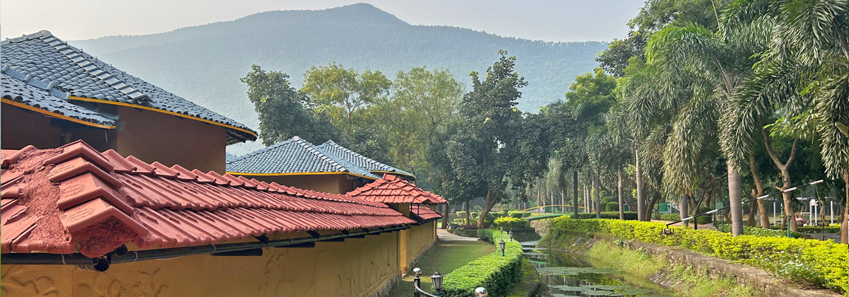 A winding pathway lined with trees and a canal with the Panchet hill in the background